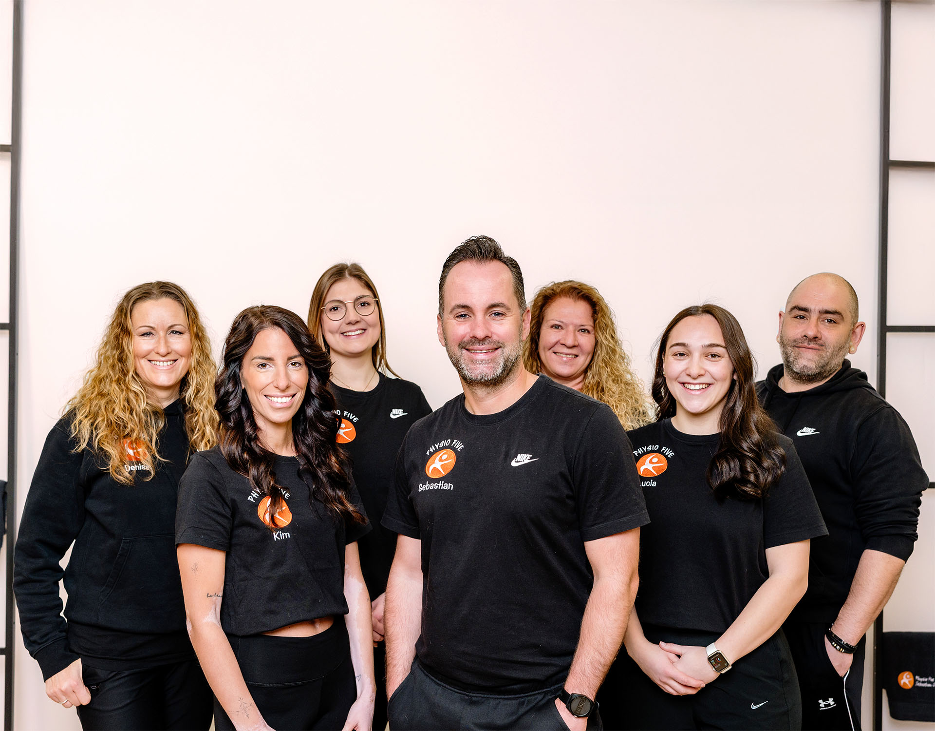 Team der Physio Five Physiotherapiepraxis mit angeschlossenem Gesundheitsstudio in Merenberg, in einheitlichen schwarzen Shirts mit Praxislogo posierend.