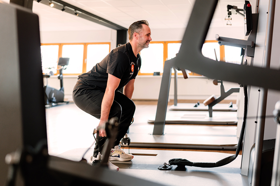 Ein Mann absolviert ein Krafttraining mit einem Kabelzug in einem modernen Gesundheitsstudio der Physio Five Physiotherapiepraxis in Merenberg, die klassische Physiotherapie mit medizinischem Gesundheitstraining verbindet.