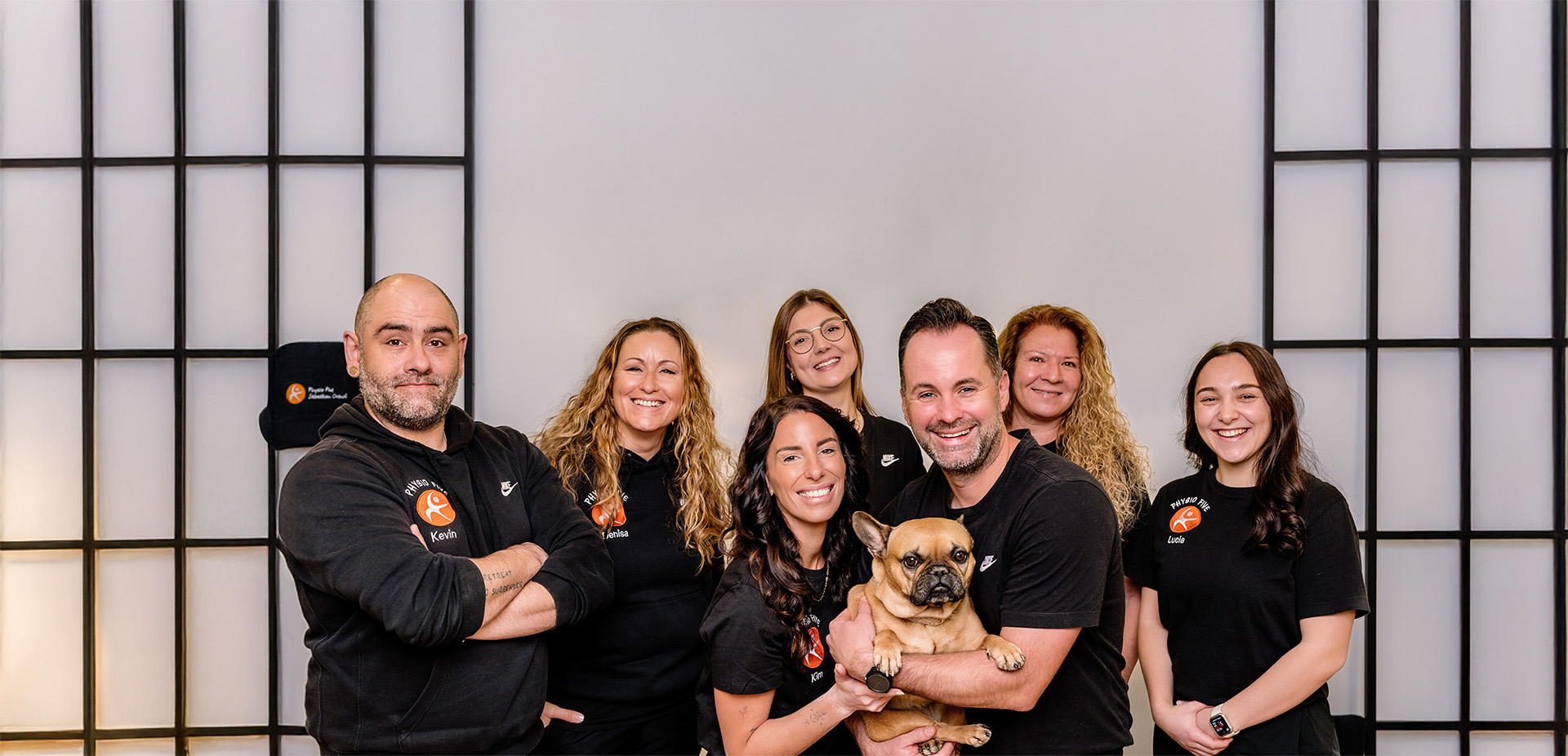 Das Team der Physio Five Physiotherapiepraxis in Merenberg, das Patienten mit klassischer Physiotherapie und modernem Gesundheitstraining begleitet, posiert mit einem Hund im Praxisraum.