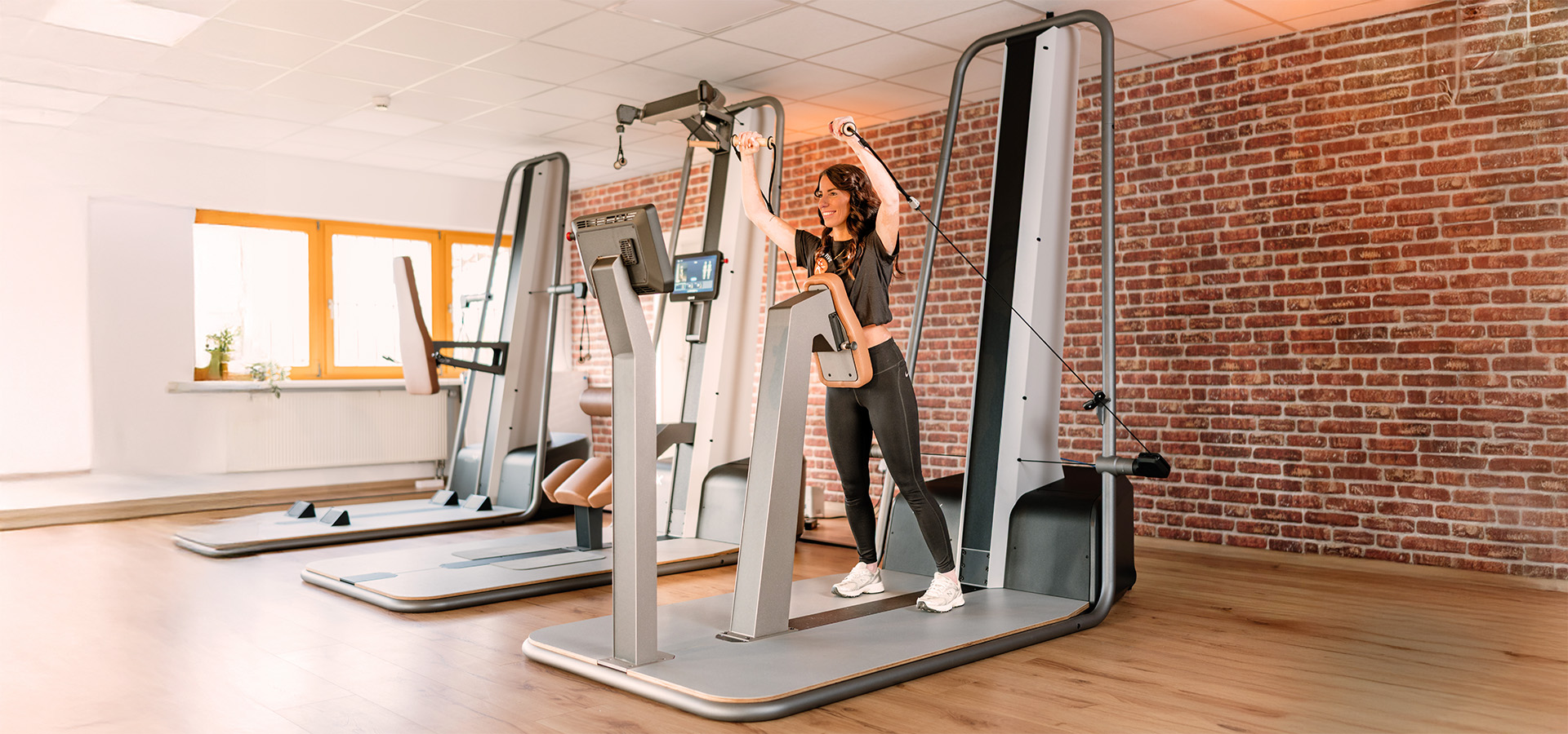 Frau trainiert mit einem Kabelzuggerät in einem modernen Gesundheitsstudio von Physio Five, das klassische Physiotherapie mit medizinischem Gesundheitstraining und modernen Systemen wie milon verbindet.