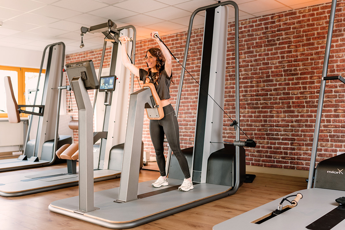 Eine Frau führt ein Kabelzugtraining an modernem milon-Gerät im Gesundheitsstudio von Physio Five durch – einer Physiotherapiepraxis in Merenberg, die Schmerzreduktion, Beweglichkeit und den sicheren Übergang von Therapie zu dauerhaftem Training fördert.