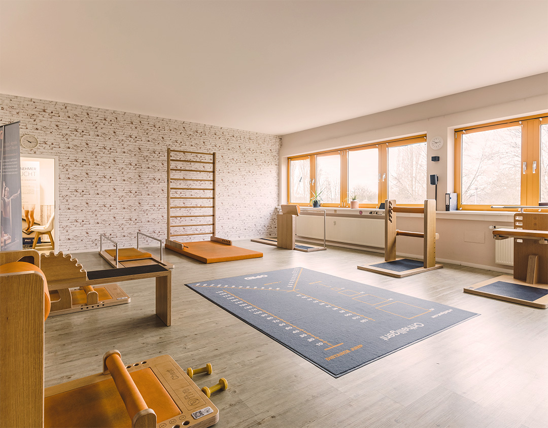 Heller, moderner Physiotherapie-Raum mit Holztrainingsgeräten, Matten und viel natürlichem Licht – charakteristisch für die Praxis Physio Five, die klassische Physiotherapie mit medizinischem Gesundheitstraining verbindet.
